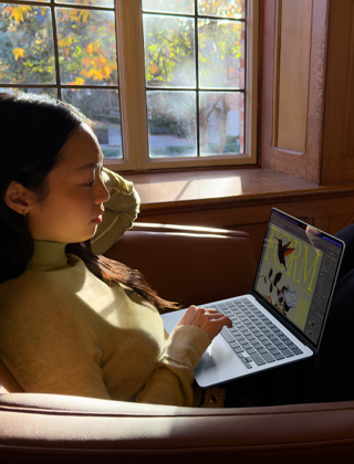 Eine Person sitzt auf einem Stuhl und arbeitet mit einem MacBook Air